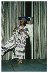 A woman in purple and white dress standing on stage.