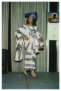 A woman in purple and white dress standing on stage.