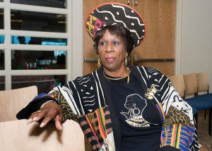 A woman wearing a hat and sitting on a chair.