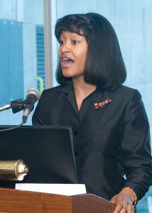 A woman in black shirt speaking at podium.