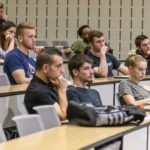 A group of people sitting in front of desks.