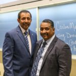 Two men in suits posing for a picture.